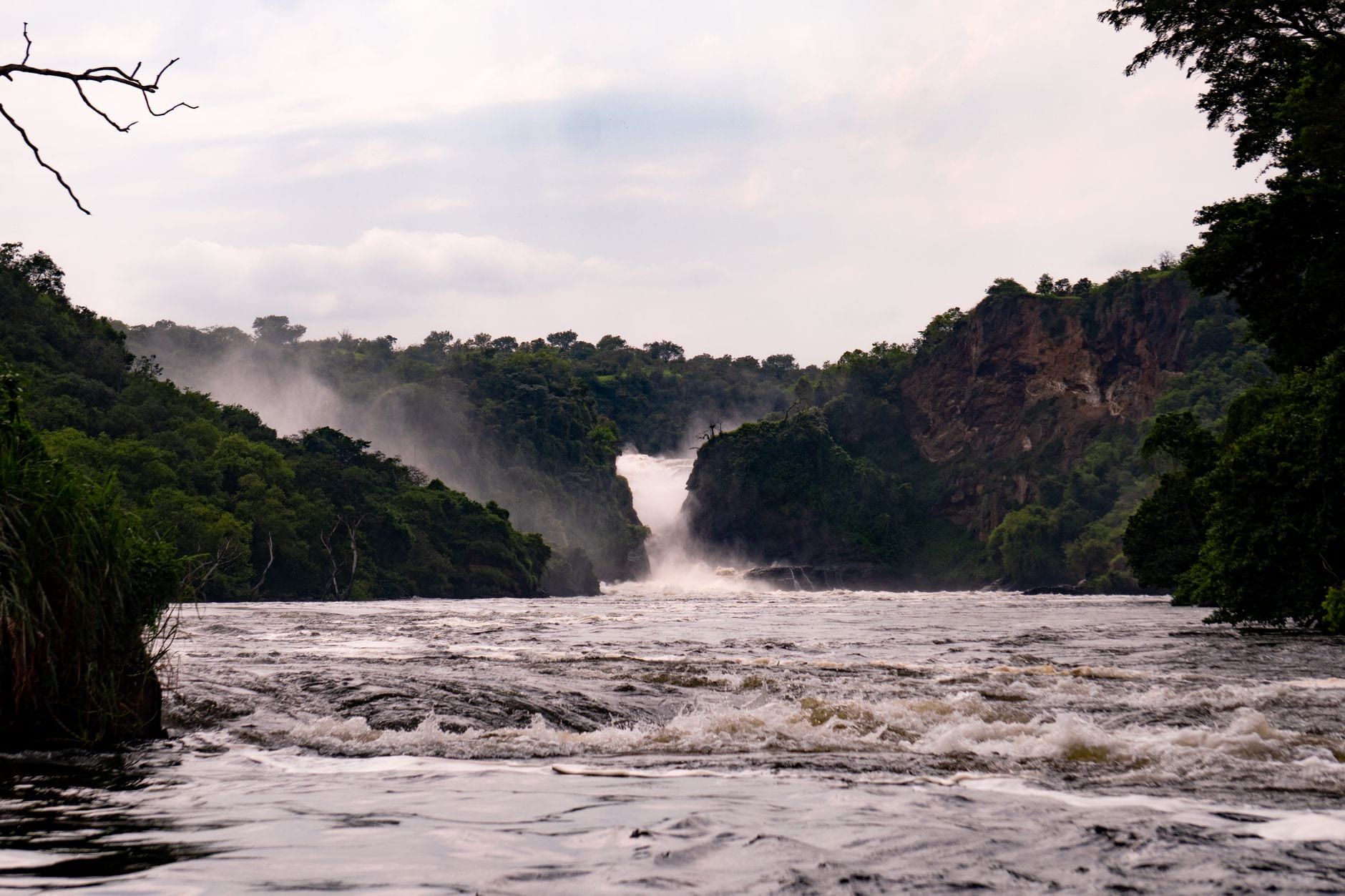 Murchison Falls stort zich door een rotsachtige kloof in het stromende water van de Victoriameren-Nijl, omringd door weelderig groene heuvels in Murchison Falls National Park.